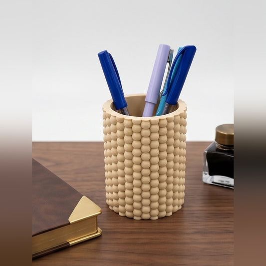 Bobble pen pot on a walnut desk holding coloured pens, beside a leather notebook and ink bottle