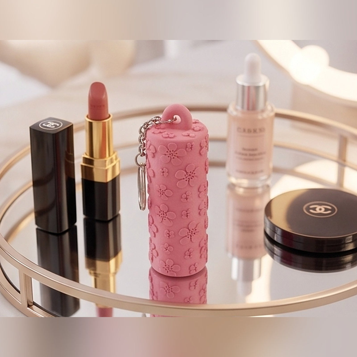 Floral design lip balm holder on a mirrored vanity tray beside lipstick and skincare
